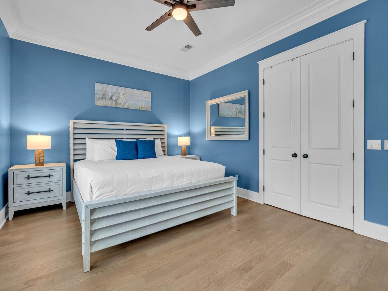 Une chambre à coucher comprenant un lit, des tables de chevet, un ventilateur de plafond et une armoire.