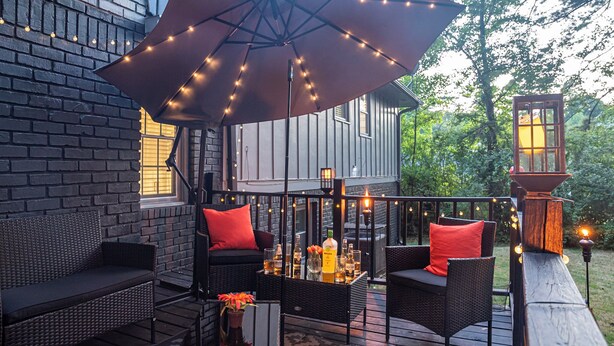 Eine Terrasse mit Gartenmöbeln, Lichterketten und einer Laterne.