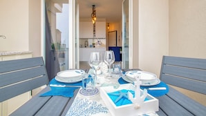 Una tavola imbandita con piatti, bicchieri e un centrotavola, con vista su una cucina e una porta sullo sfondo.