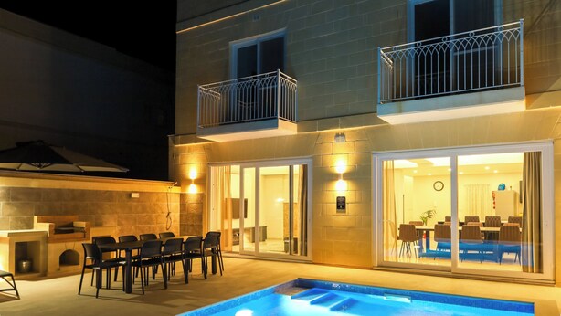 Un bâtiment à deux étages doté d’une piscine, d’un espace repas extérieur et d’un barbecue.