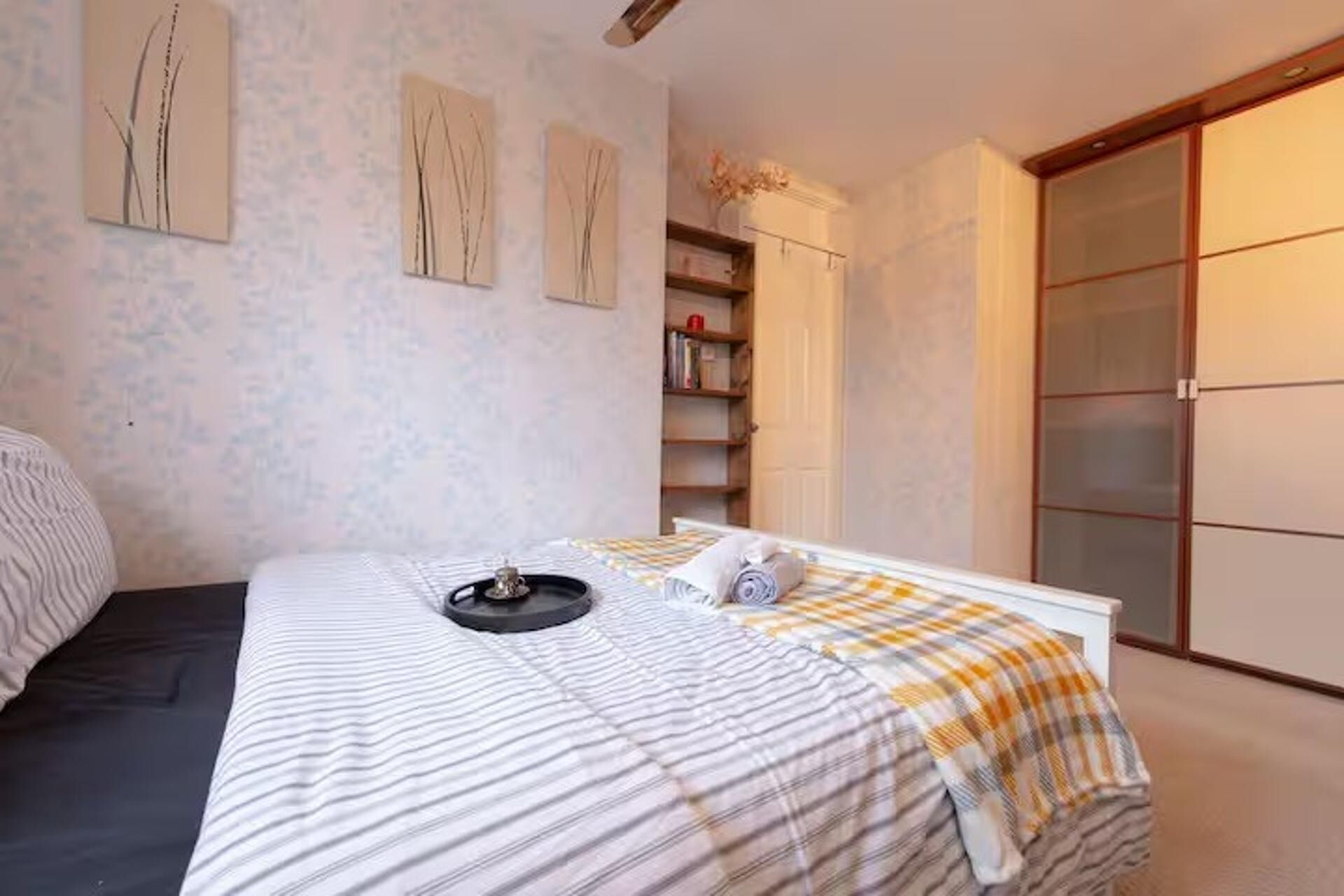 Un dormitorio con cama, mesita de noche, lámpara y armario.