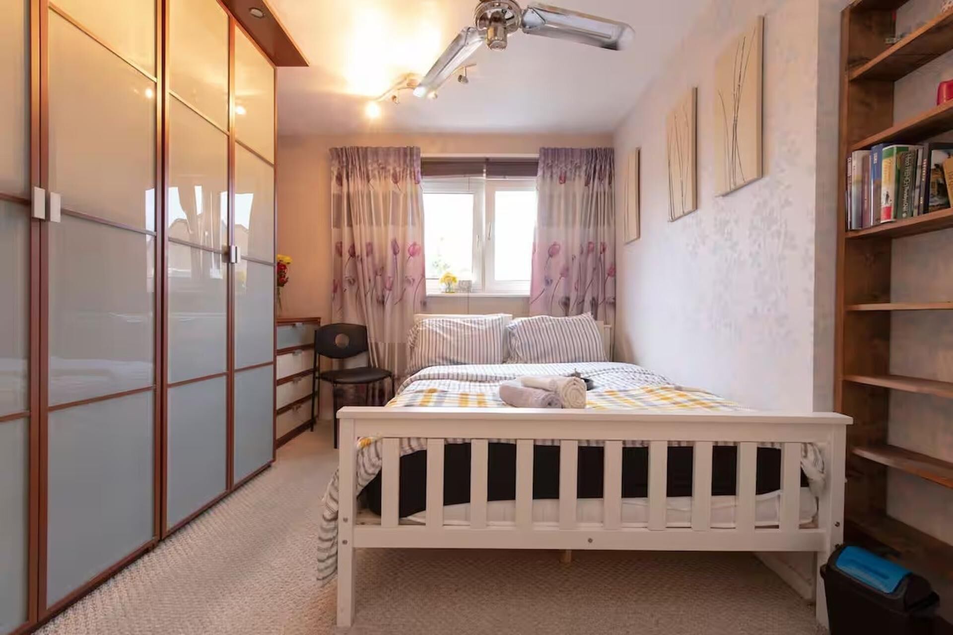 A bedroom with a bed, a desk, a chair, a wardrobe, and a bookshelf.