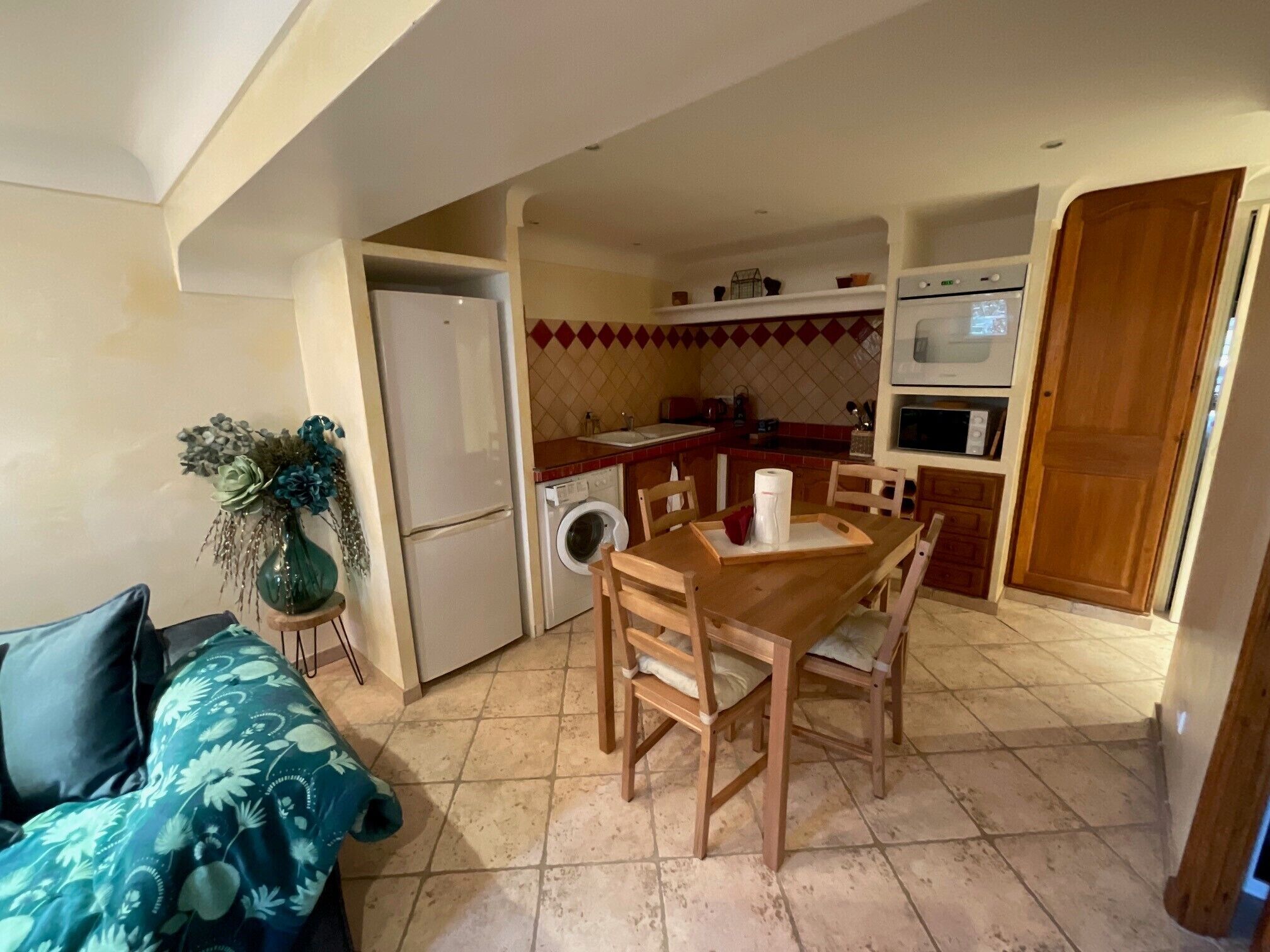 A compact kitchen with a dining area, a washing machine, and a refrigerator.