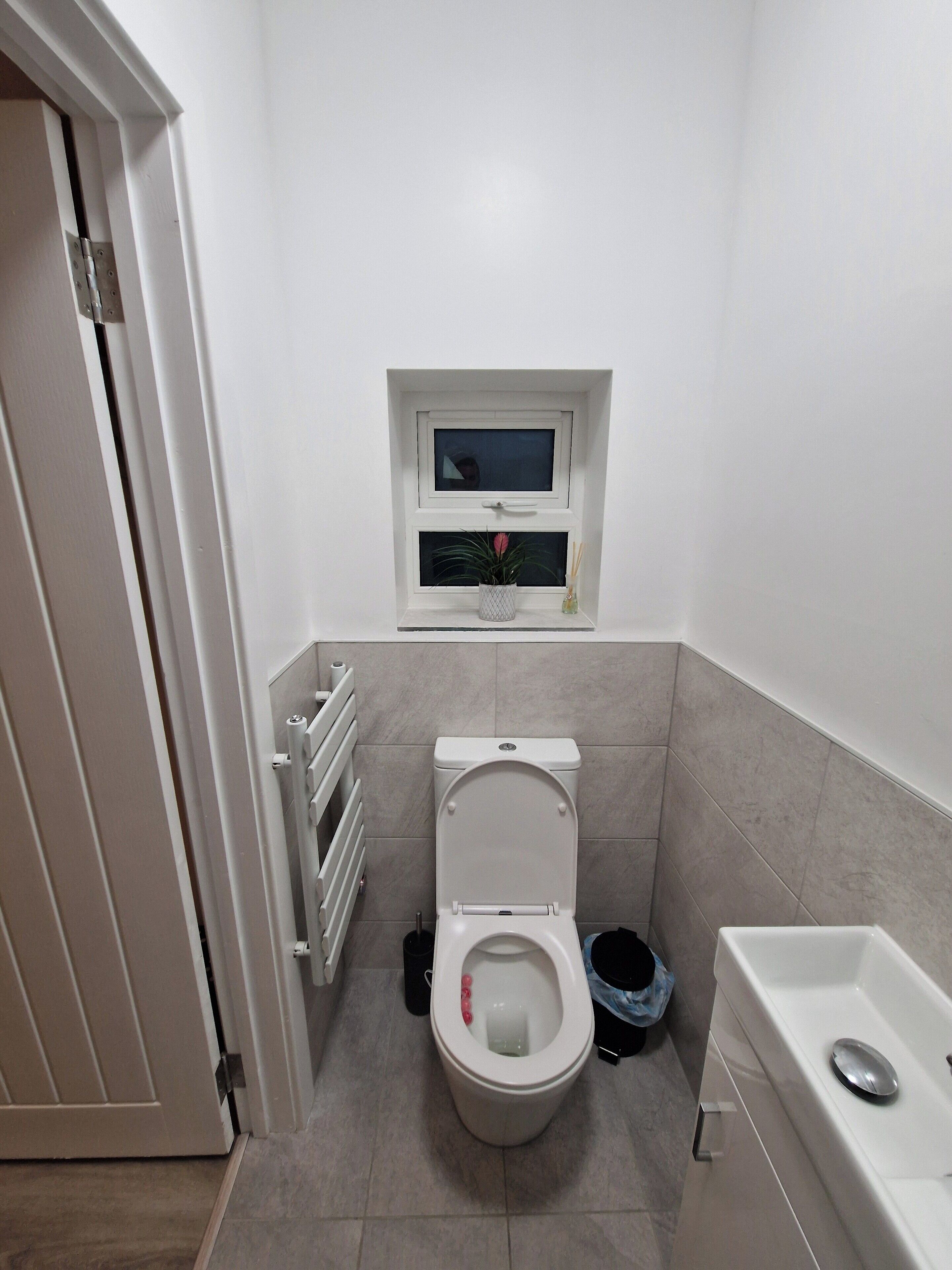 Ein kleines Badezimmer mit Toilette, Fenster, Heizkörper und Badewanne.