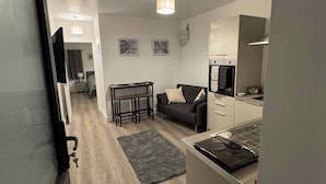 A compact living space with a kitchenette, a sofa, a dining table, and a small rug. - Cozy Apartment at Highbanks The Annex (Newhaven)