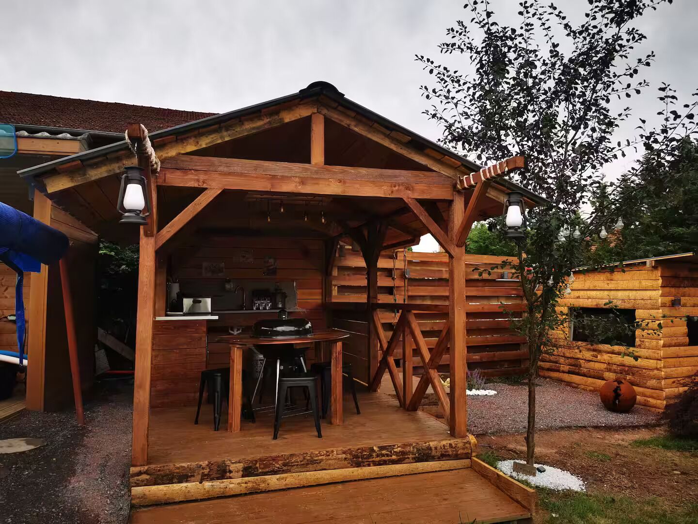 Une cabane en bois rustique dotée d’un porche abrité, d’une table à manger et de chaises.
