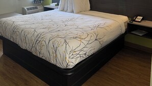 A hotel room with a large bed, two bedside tables, a telephone, and a window with a curtain. - Cozy 1 - room hotel in charming Columbus and Ft. Moore with AC, WiFi (Columbus)