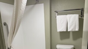 A bathroom with a bathtub, toilet, and a towel rack with two towels. - Cozy 1 - room hotel in charming Columbus and Ft. Moore with AC, WiFi (Columbus)