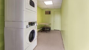 A laundry room with stacked washers and dryers, a table, and a door. - Cozy 1 - room hotel in charming Columbus and Ft. Moore with AC, WiFi (Columbus)