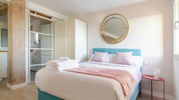 Een slaapkamer met een bed, een ronde spiegel, een nachtkastje en een kledingkast.