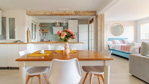 Een moderne keuken met een houten kookeiland, witte stoelen en een bloevas.