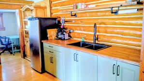 A kitchen with wooden paneling, a stainless steel refrigerator, a sink, and a coffee maker.