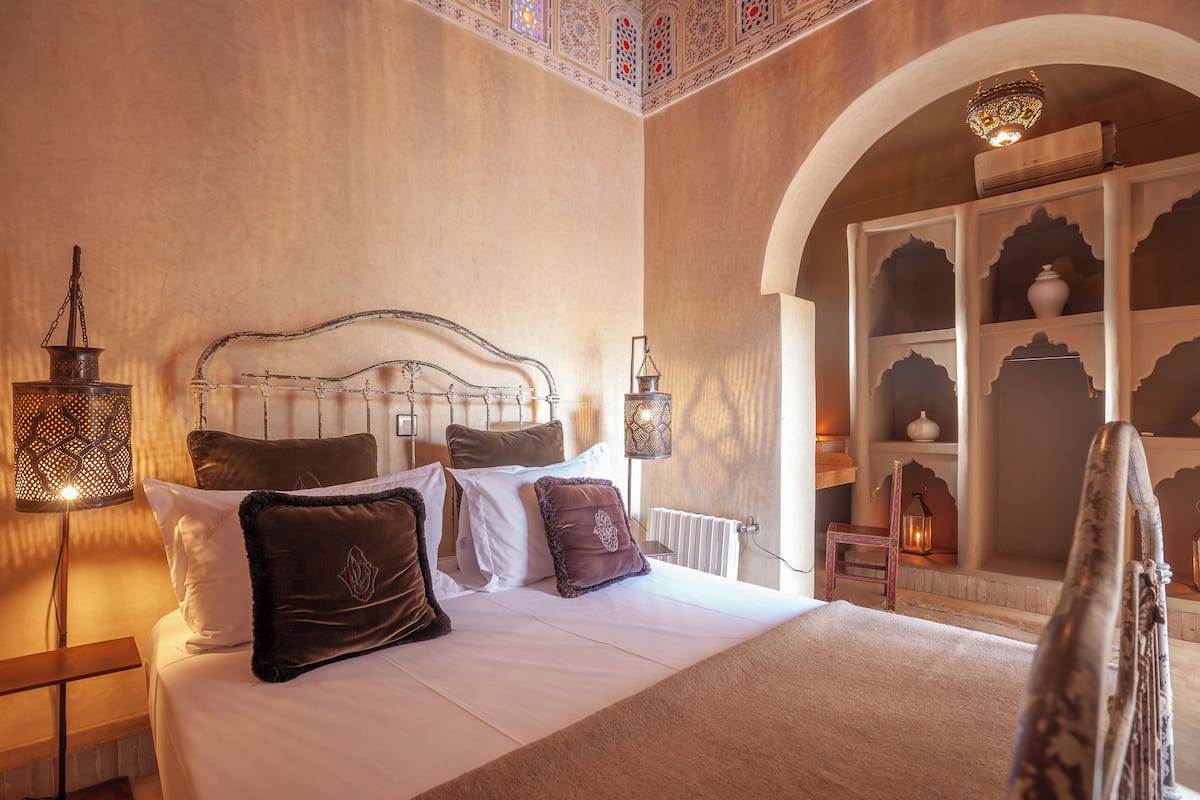 A bedroom with a large bed, ornate headboard, and decorative lamps.