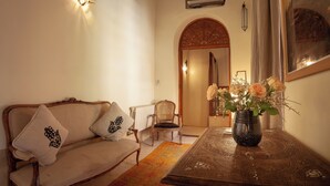 A cozy living room with a sofa, a chair, a table with a vase of flowers, and a decorative wall hanging. - RIAD BOHEMIA (Marrakech)