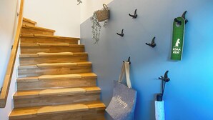 A wooden staircase with a basket and a tote bag hanging on the wall.