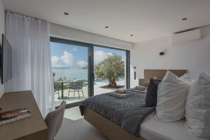 Ein modernes Schlafzimmer mit einem großen Bett, einem Schreibtisch und Meerblick.