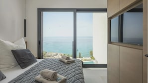 A bedroom with a bed, a TV, and a view of the sea.