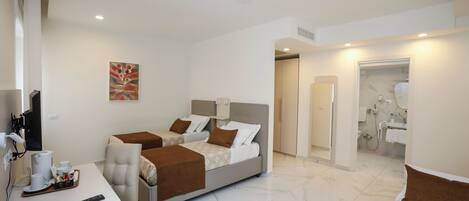A hotel room with two beds, a desk with a tray of breakfast items, a television, and a bathroom visible through an open door.