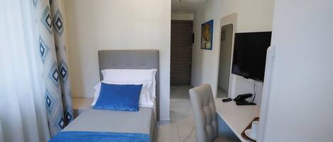 A hotel room with a bed, a desk with a computer, and a television.