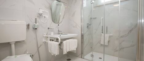 A modern bathroom with a toilet, sink, and glass-enclosed shower.