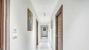 A hallway with marble flooring, wooden doors, and framed artwork on the walls. - Vomero High Hotel (Naples)