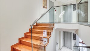A modern staircase with glass railings and wooden steps, leading to an upper floor. - Vomero High Hotel (Naples)