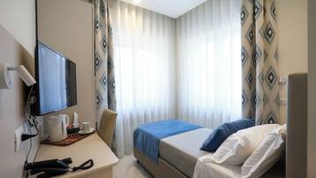Una habitación de hotel con cama, escritorio, televisor de pantalla plana, teléfono y cafetera.