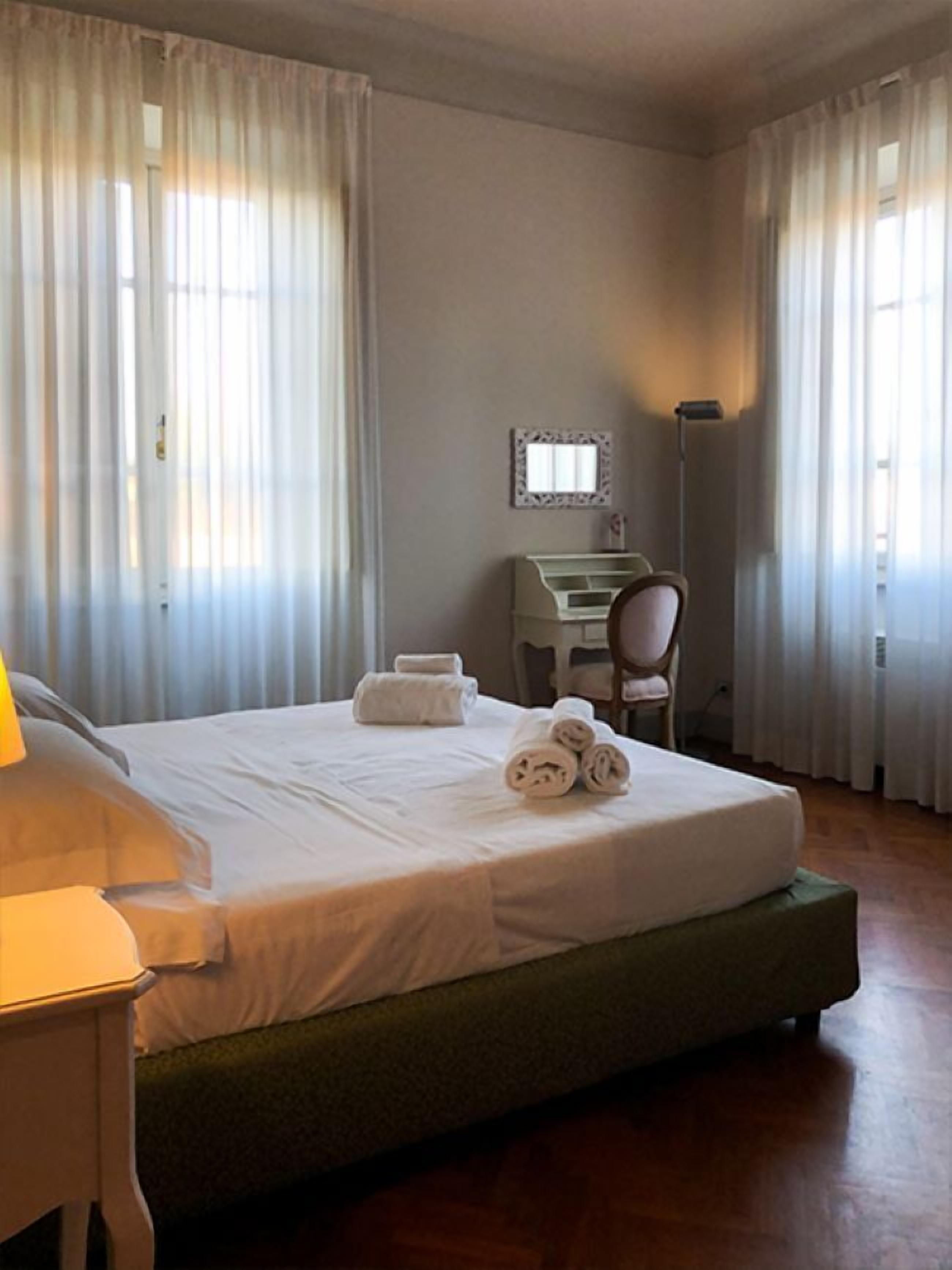 Una habitación de hotel con una cama, un escritorio, una silla y una lámpara.