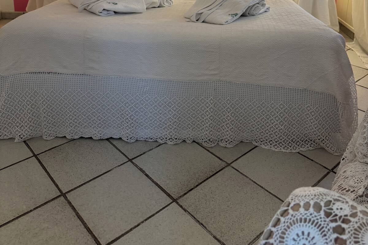 A bed with white linens, two pillows, and a decorative headboard. There are two bedside tables with lamps.