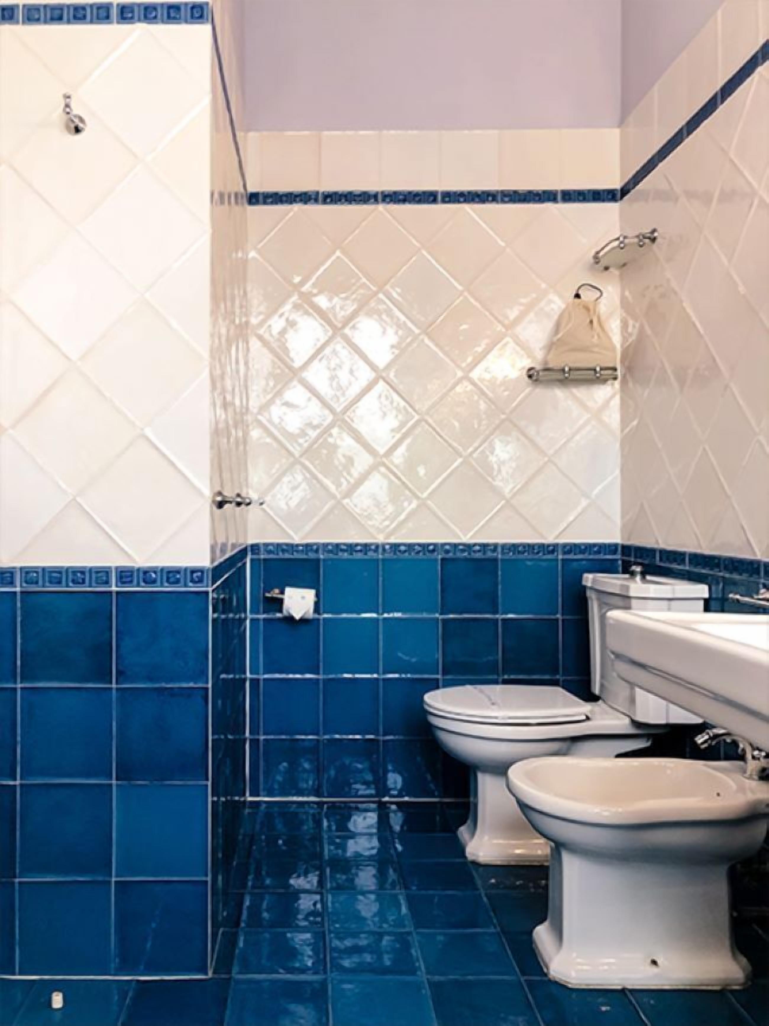 A bathroom with two toilets, a sink, and a shower.