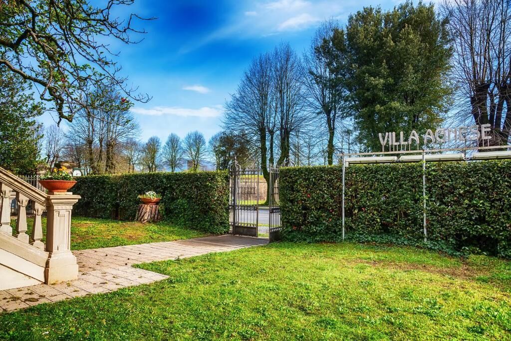 A gated entrance to Villa Agiese with a paved pathway leading to the gate.