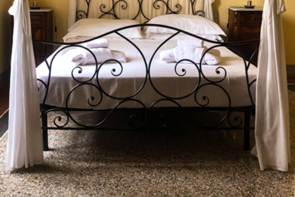 A four-poster bed with a canopy, white bedding, and two bedside tables.