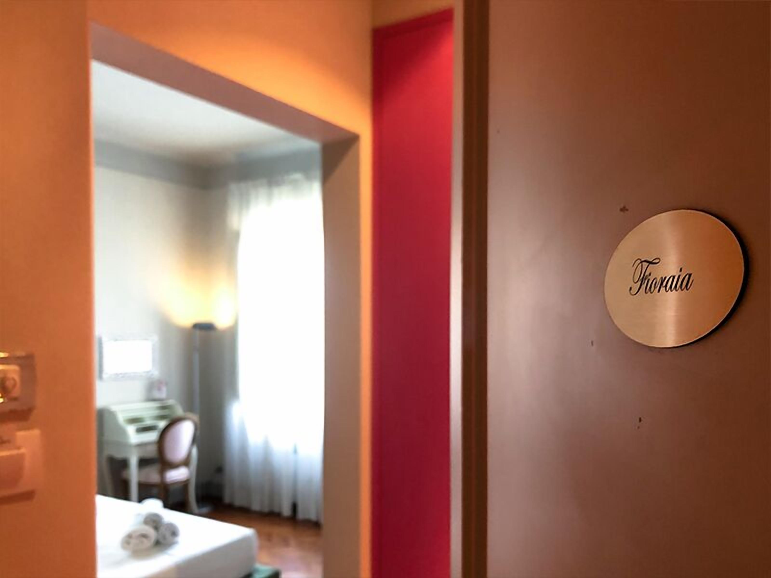 Una camera d'albergo con un letto, un tavolino e una sedia. Sul muro è presente un cartello con scritto 'Thoraia'.