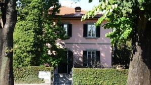 A two-story building with a pink facade, a visible entrance with steps, and a hedge in front. - Villa Agnese Bed and Breakfast (Lucca)
