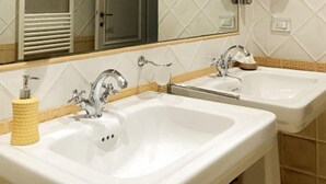 A bathroom with two sinks, a mirror, towel racks, and a soap dispenser. - Villa Agnese Bed and Breakfast (Lucca)
