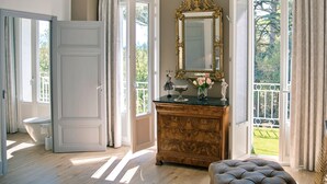 Una habitación con un aparador de madera, un espejo y una ventana con vista a un jardín.