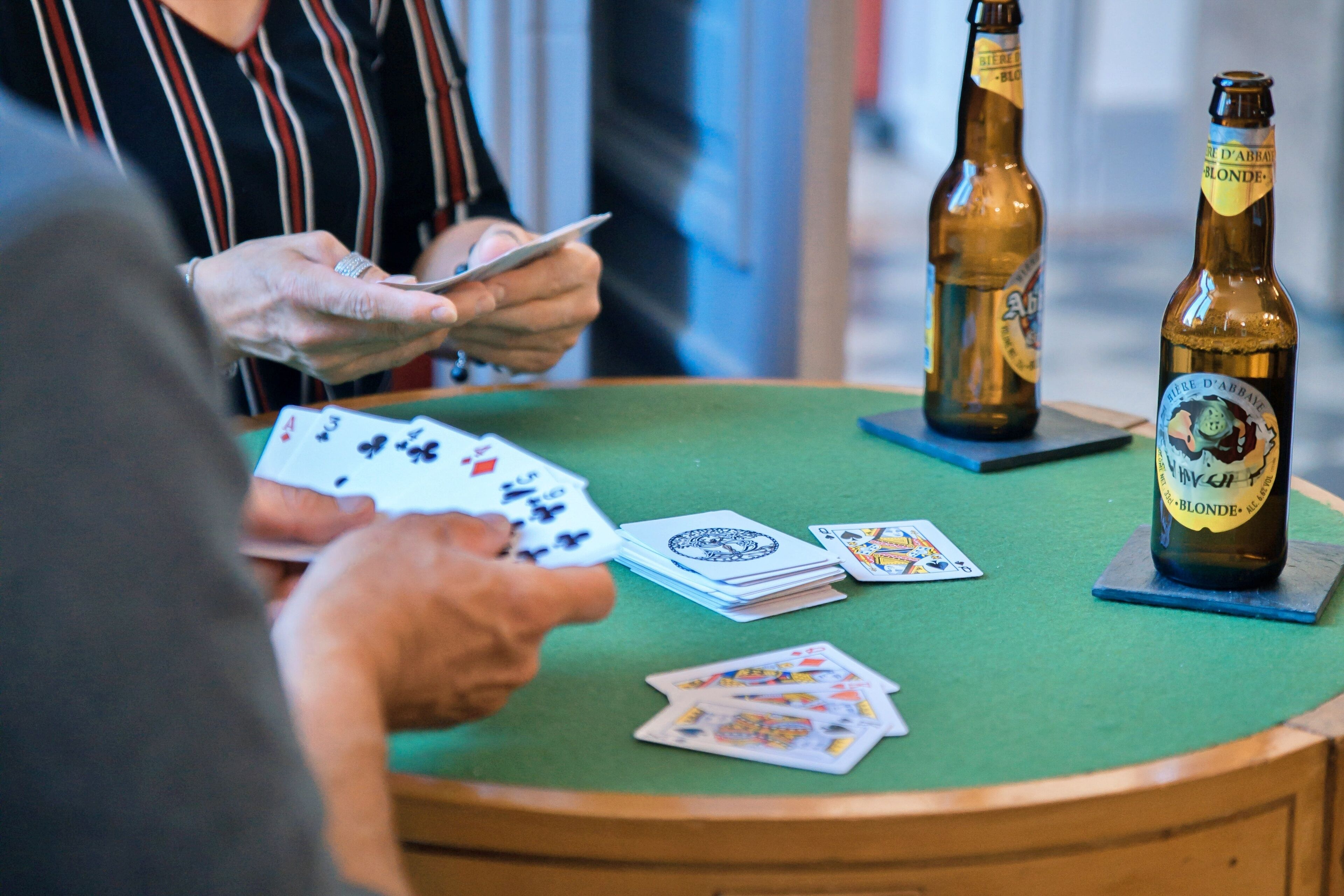 A poker game in progress with cards and beer bottles on a green table.