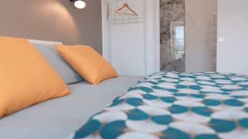 A bedroom with a bed, a hanging clothes rack, and a bathroom with a marble wall.
