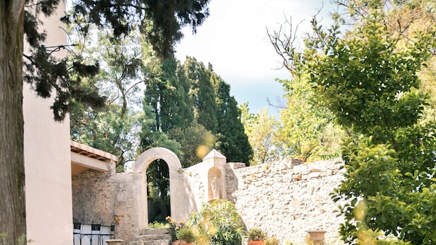Un patio de piedra con mobiliario exterior, una fuente y plantas en macetas.