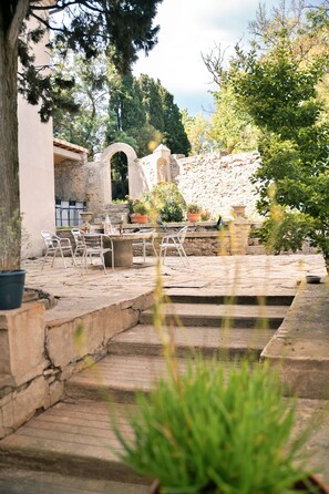 Un patio de piedra con mobiliario exterior, una fuente y plantas en macetas.