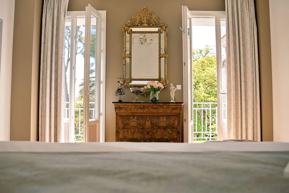 A bedroom with a bed, a dresser, a mirror, and a view of a balcony.