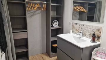 Une salle de bain moderne avec un meuble-lavabo gris, un miroir et un espace douche.