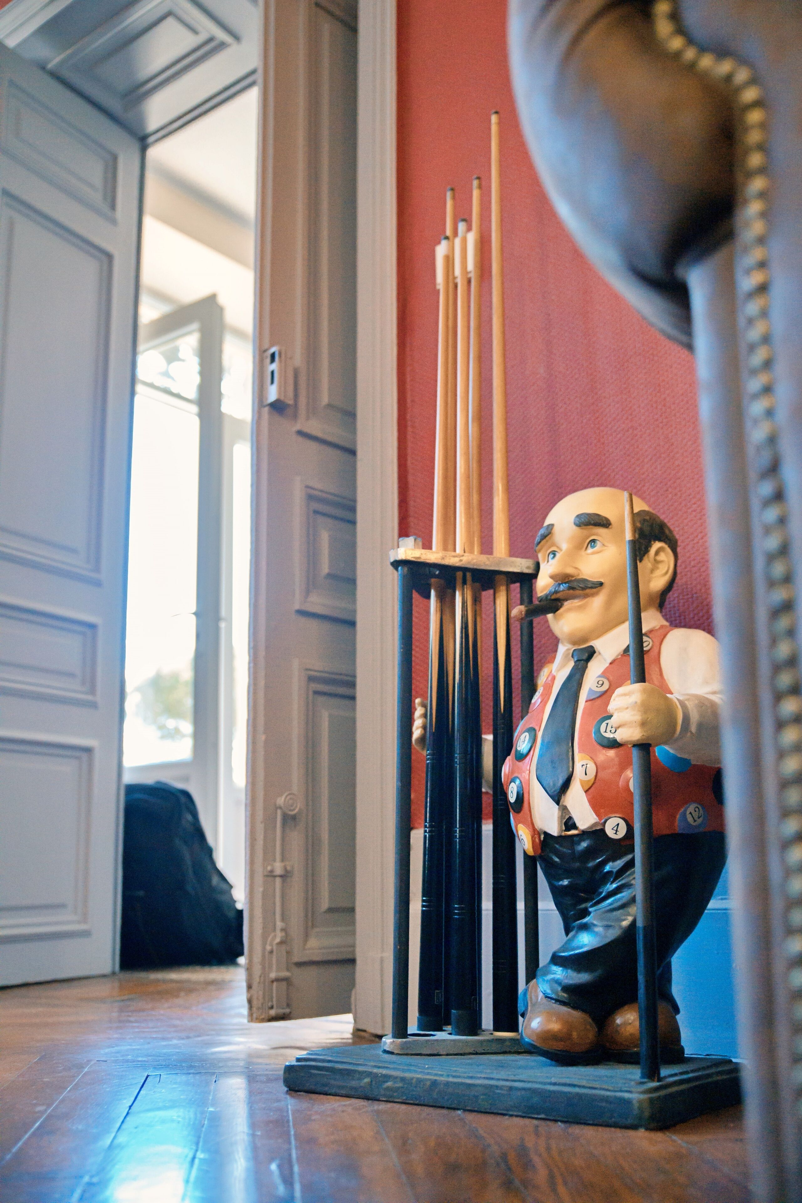 A statue of a man holding a cane, standing next to a set of pool cues.