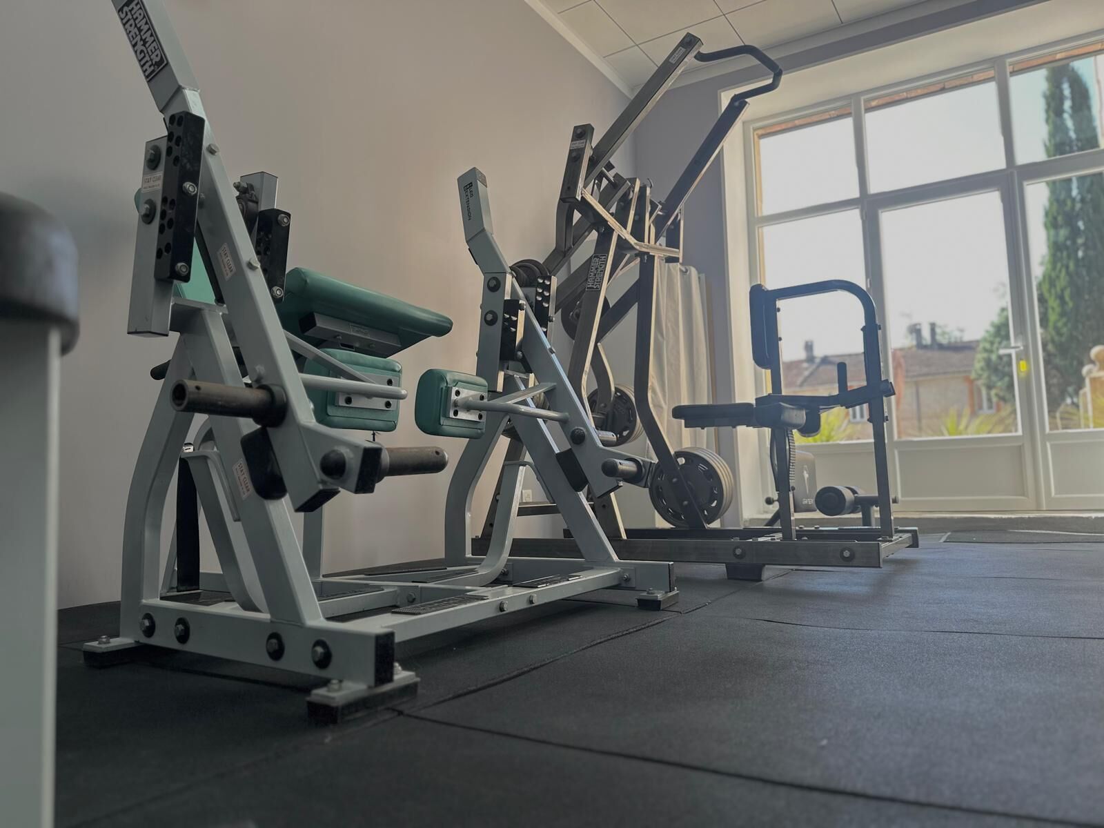A gym with exercise machines, large windows, and a view of the outside.