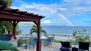 A covered outdoor area with a pool, seating, and a view of the ocean. - Thalassa. A Seaside Retreat with Pool & Infinity Oceanfront Sunrise Views (St. John)