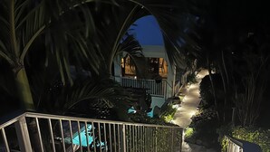 A staircase leading to a building with a pool, surrounded by palm trees and a metal railing. - Thalassa. A Seaside Retreat with Pool & Infinity Oceanfront Sunrise Views (St. John)