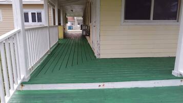 Een overdekte veranda met een groene vloer en witte leuningen.