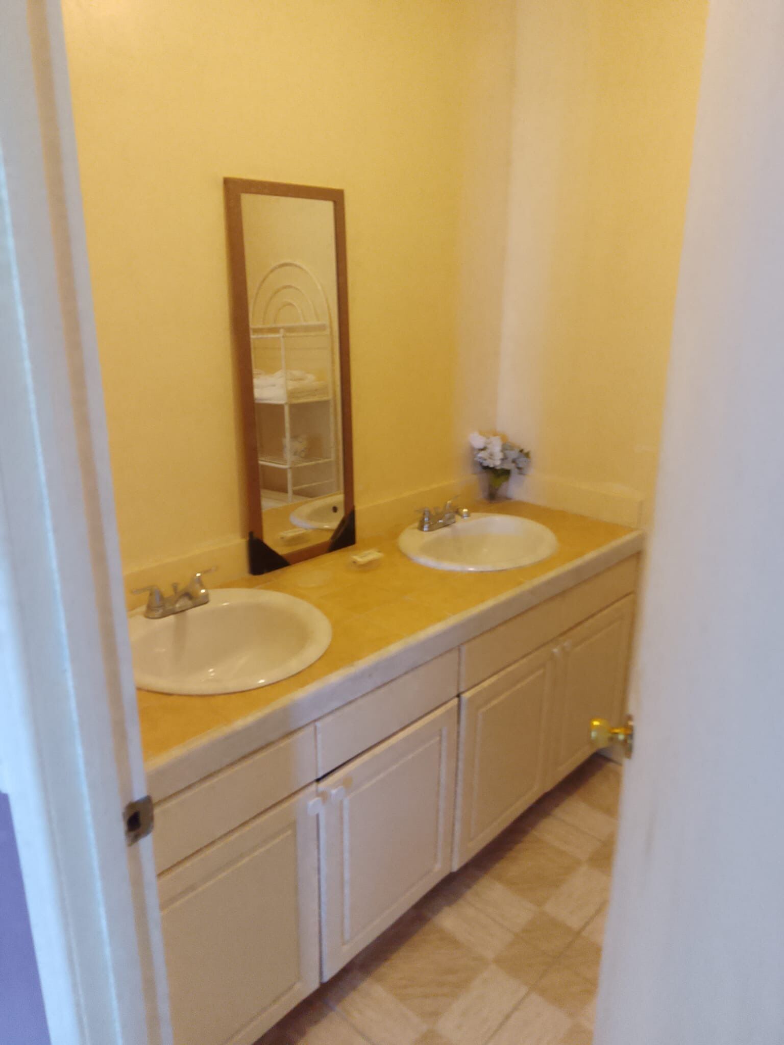 Un baño con dos lavamanos, un espejo y un perchero para toallas.
