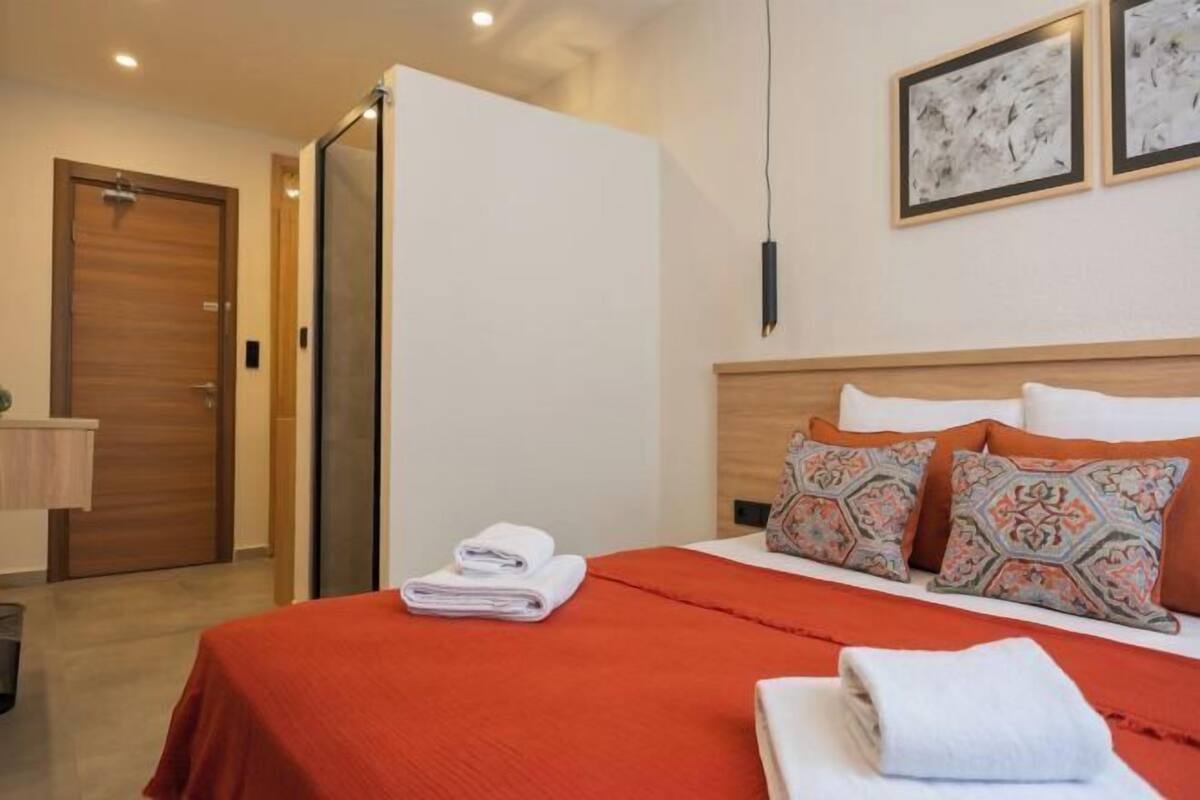 A hotel room with a bed, a wooden headboard, and two framed artworks on the wall.