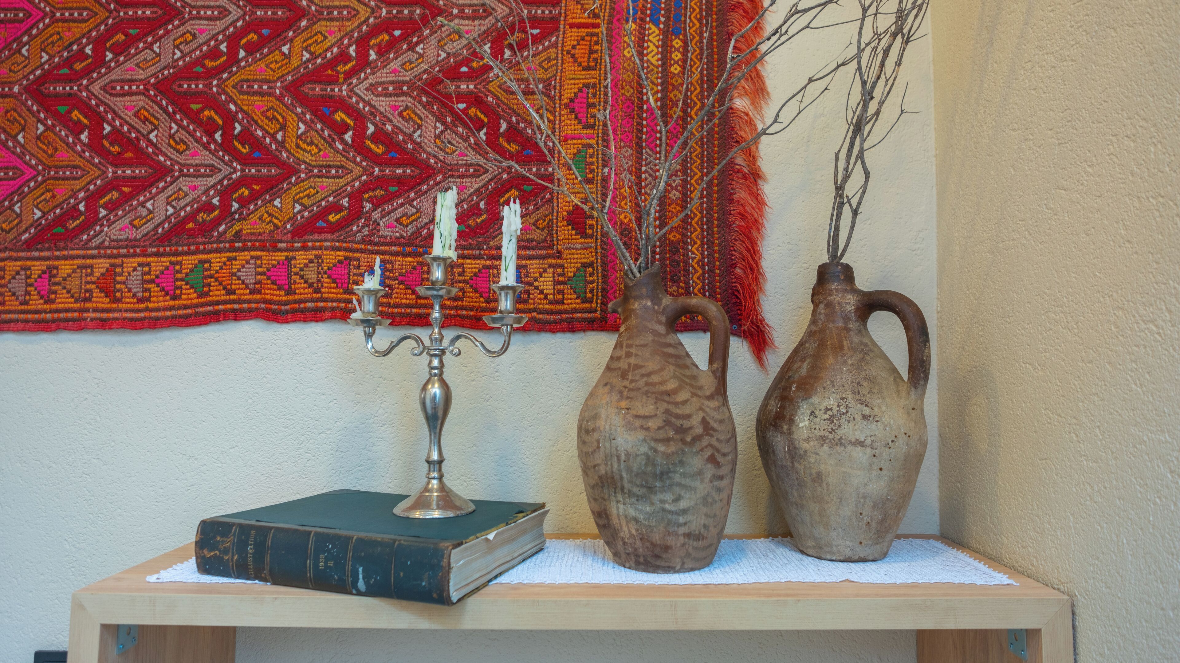 A wooden table with a book, a candelabra, and two vases.
